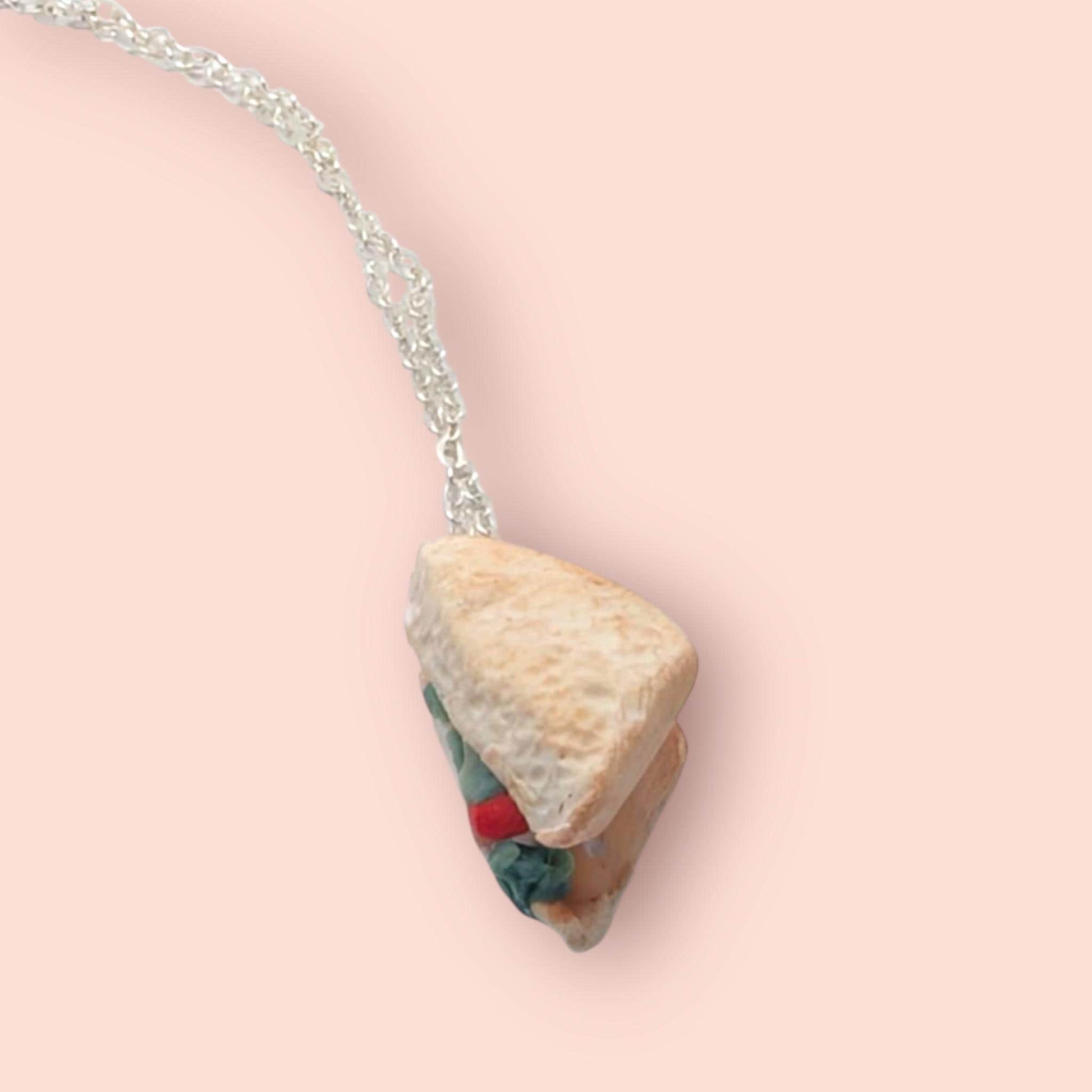 Necklace with a sand wedge pendant on a pink background