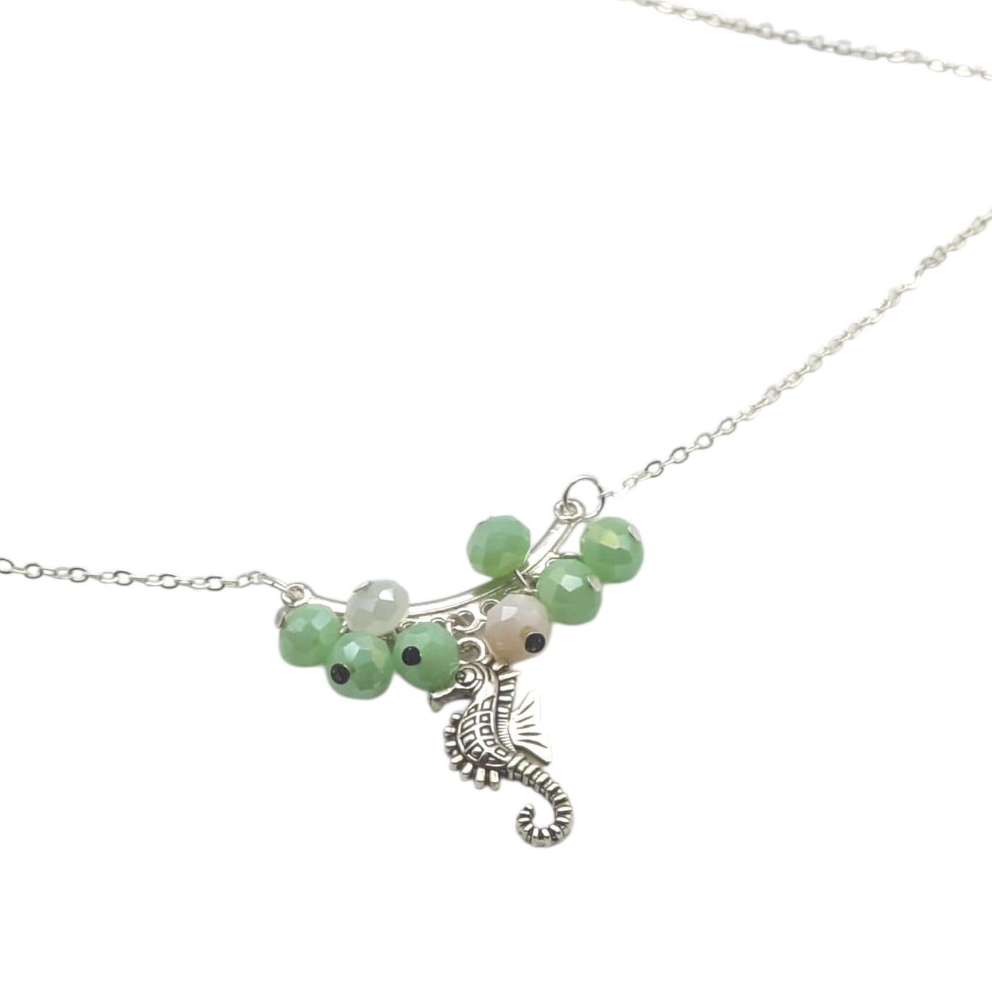 Silver chain seahorse necklace with green and pink crystals on white background 