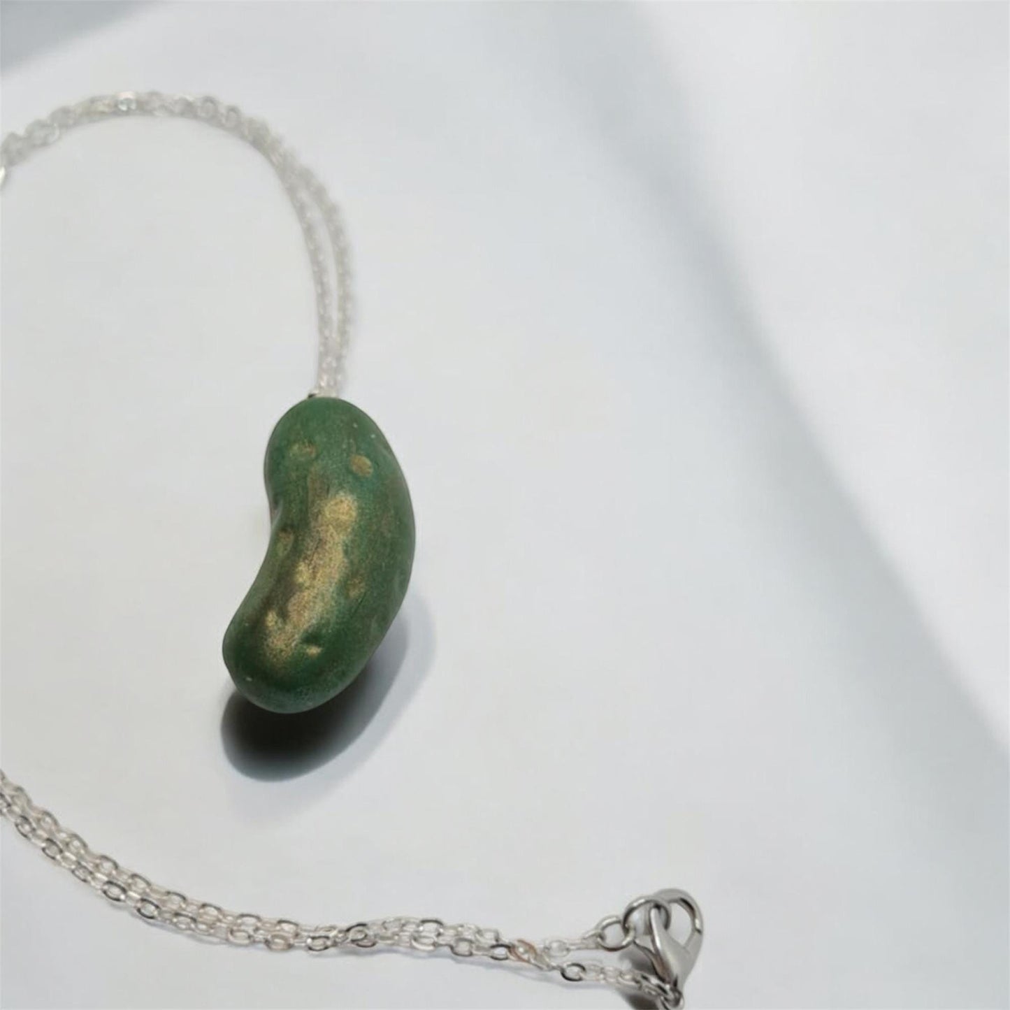 Necklace with a green dill pickle  pendant on a white background