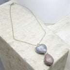 Pearl coloured heart and tear drop necklace with silver chain on a stone background