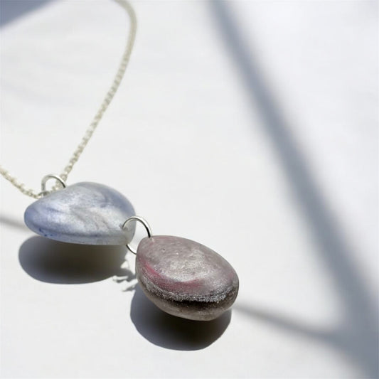Double pendant necklace blue pearlescent heart and pink pearlescent tear drop with silver chain on a white background 