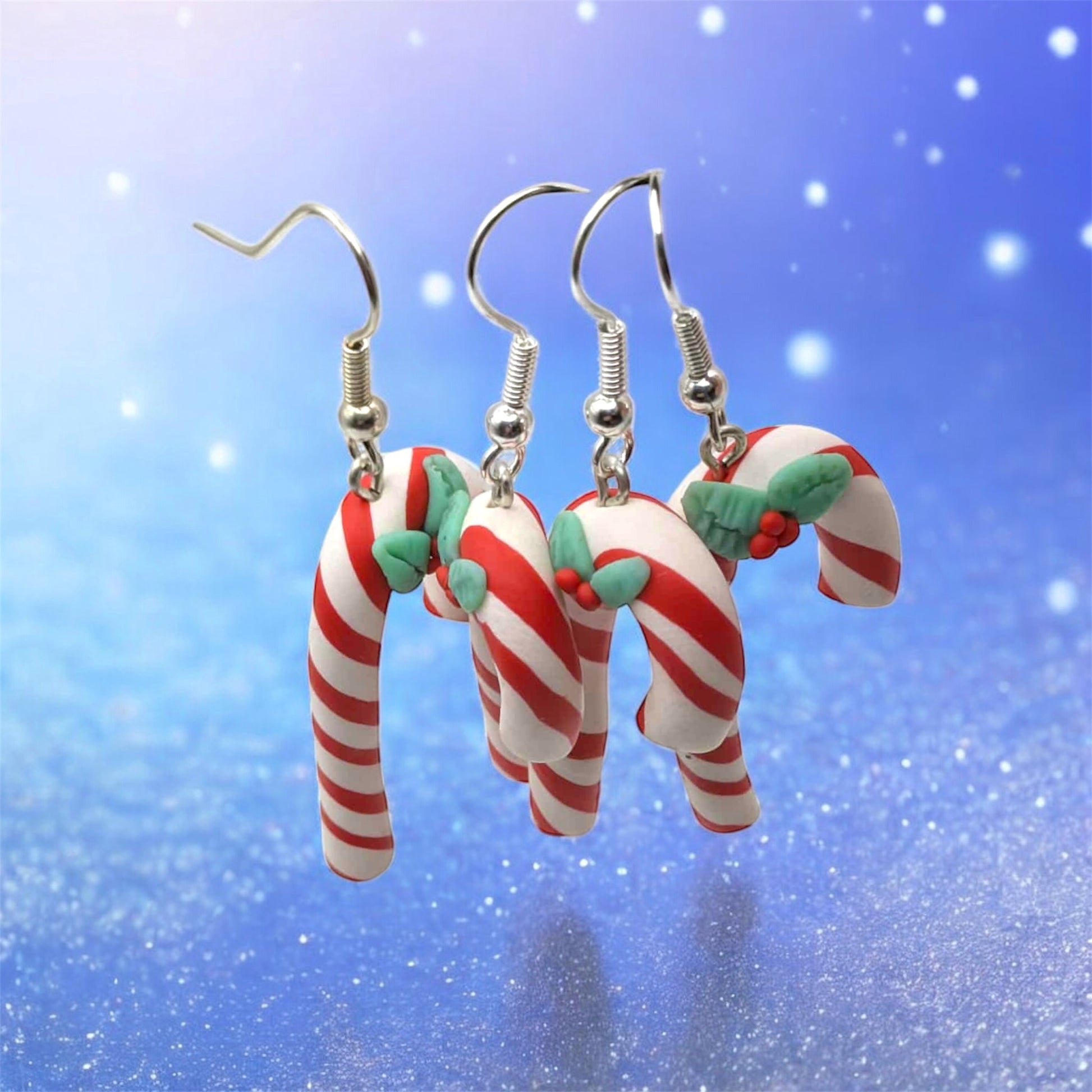 Candy cane-shaped earrings on a blue snowy background