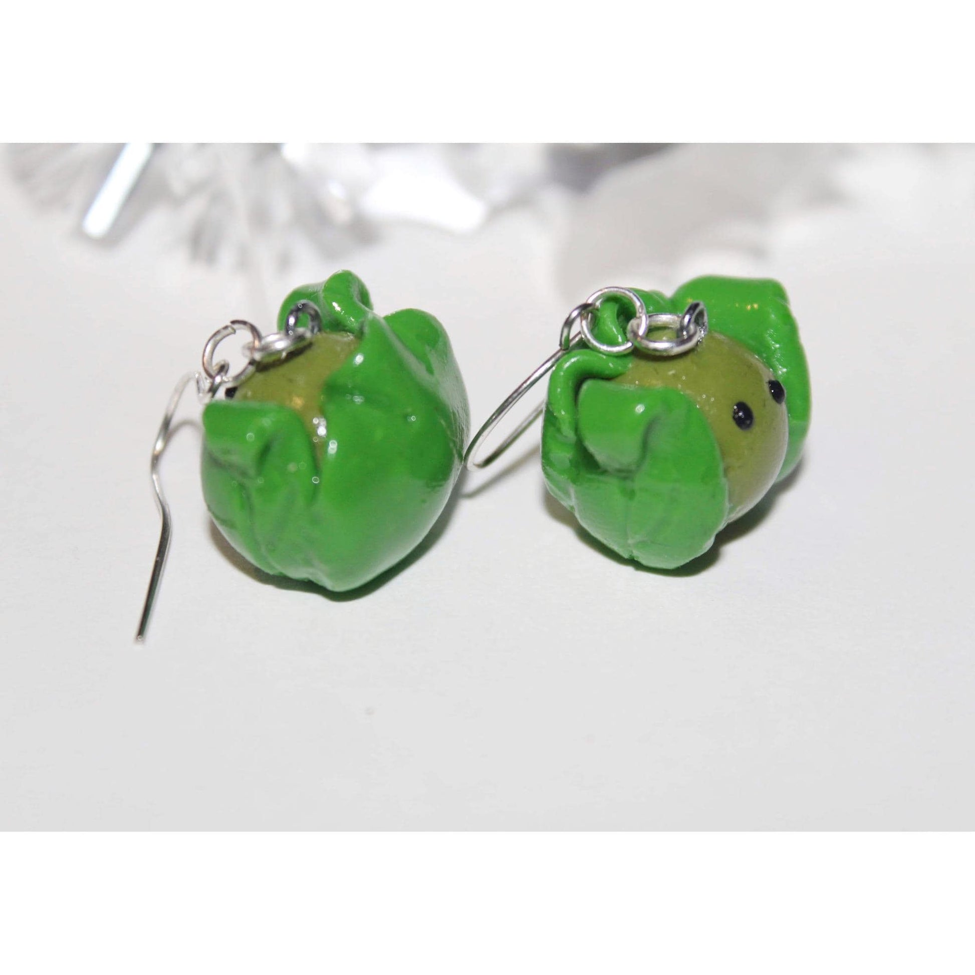 Green sprout shaped earrings on a white background