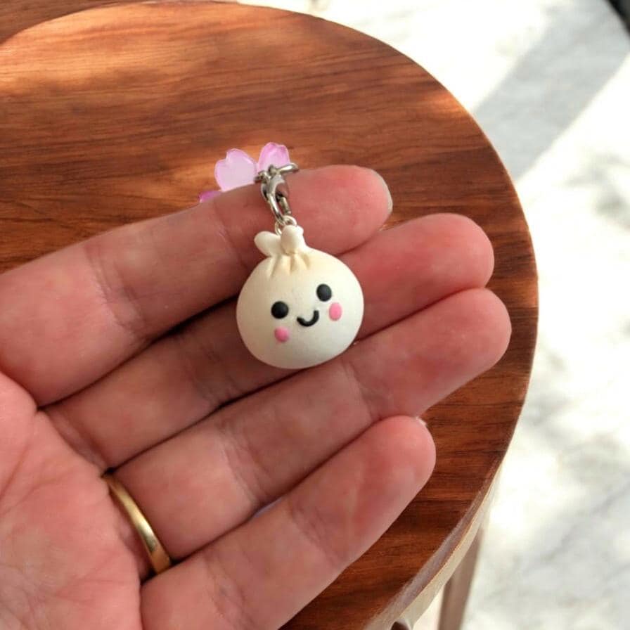 Small white charm with a face held in a hand on a wooden surface