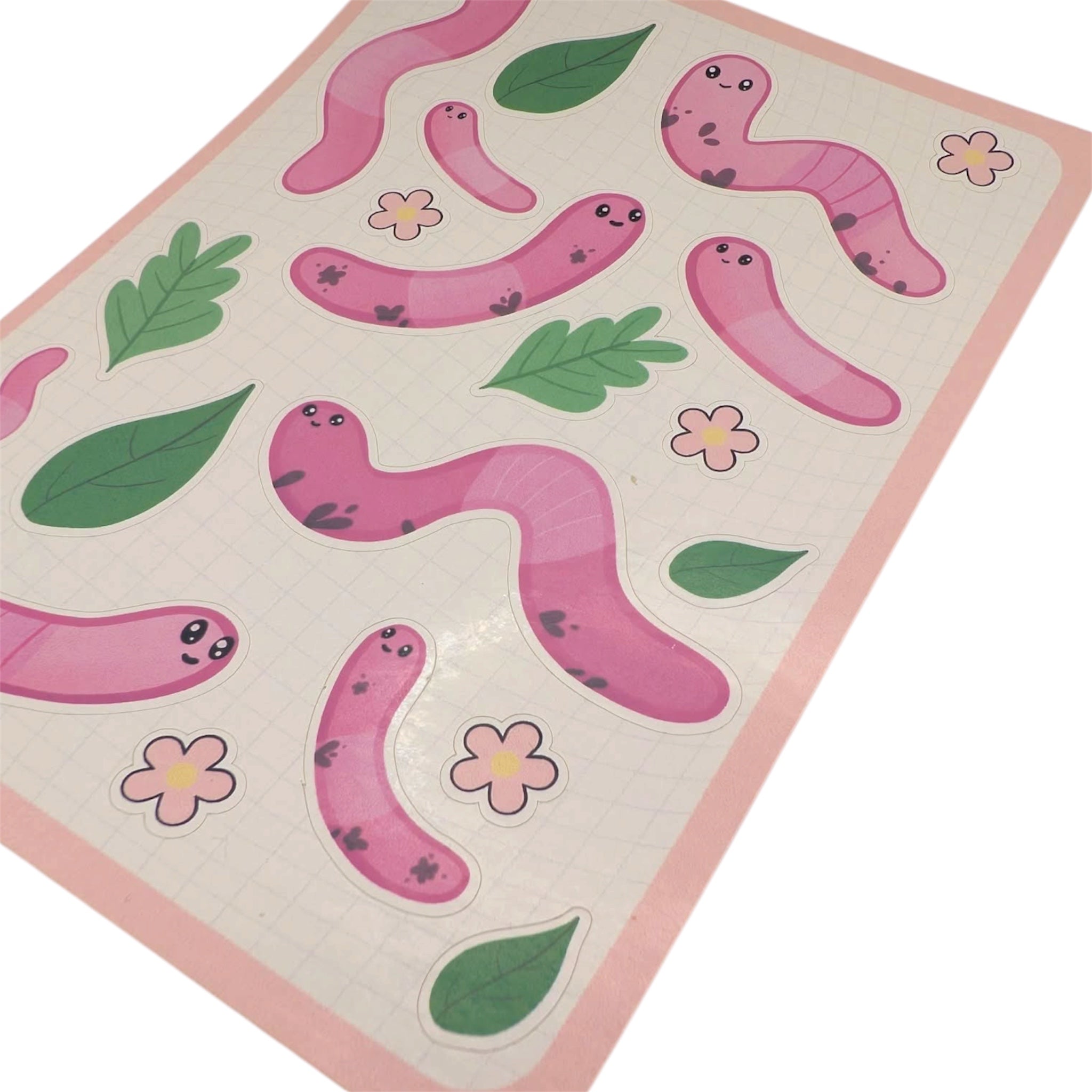 Close up of pink worm sticker sheet with cartoon earthworms, leaves and flowers shown on a white background 