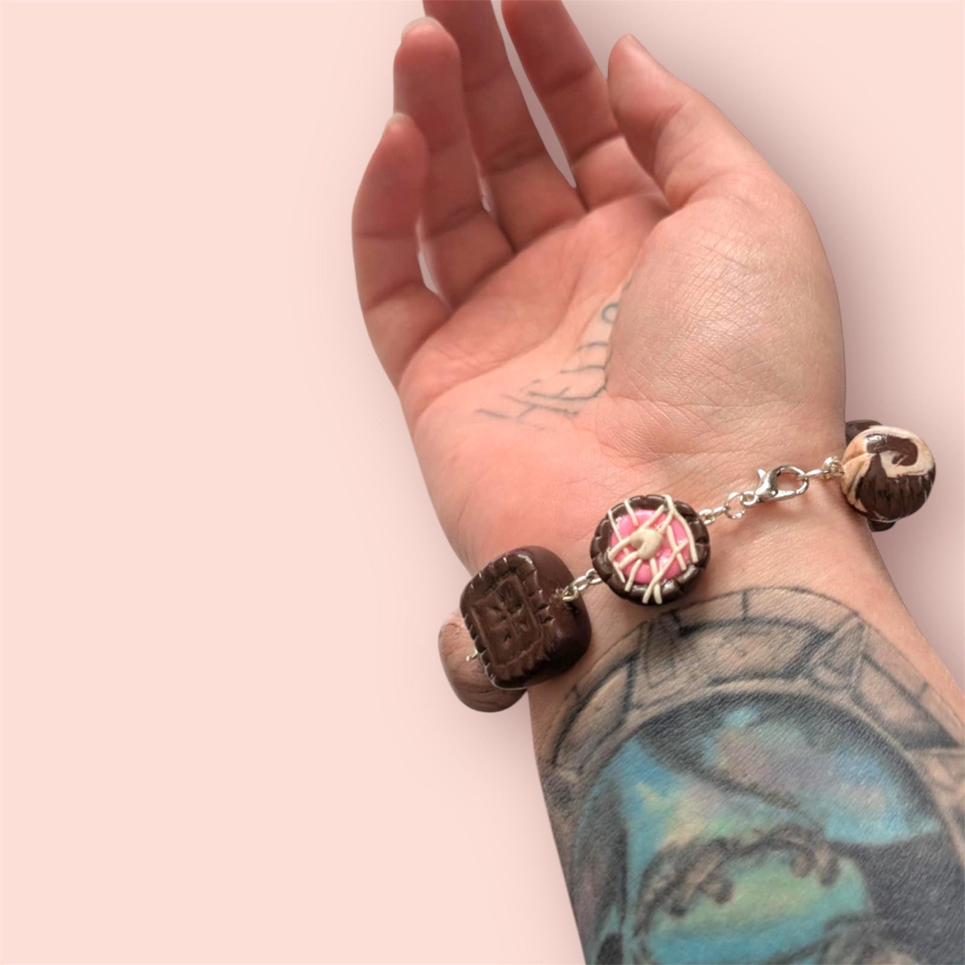 Hand wearing a bracelet with wooden beads on a light pink background
