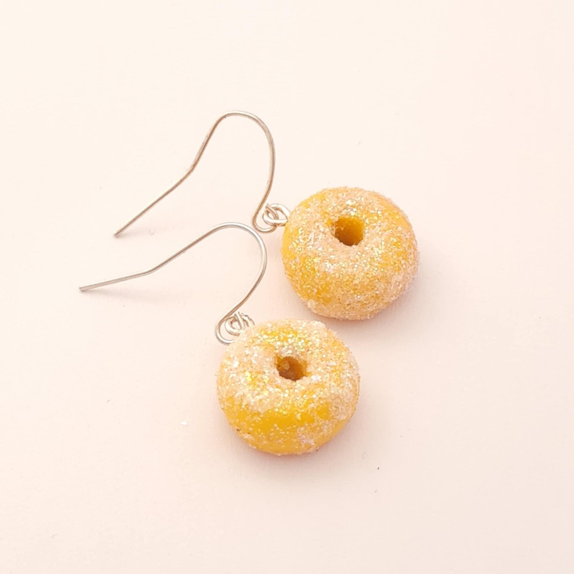 Donut-shaped earrings on a light pink background