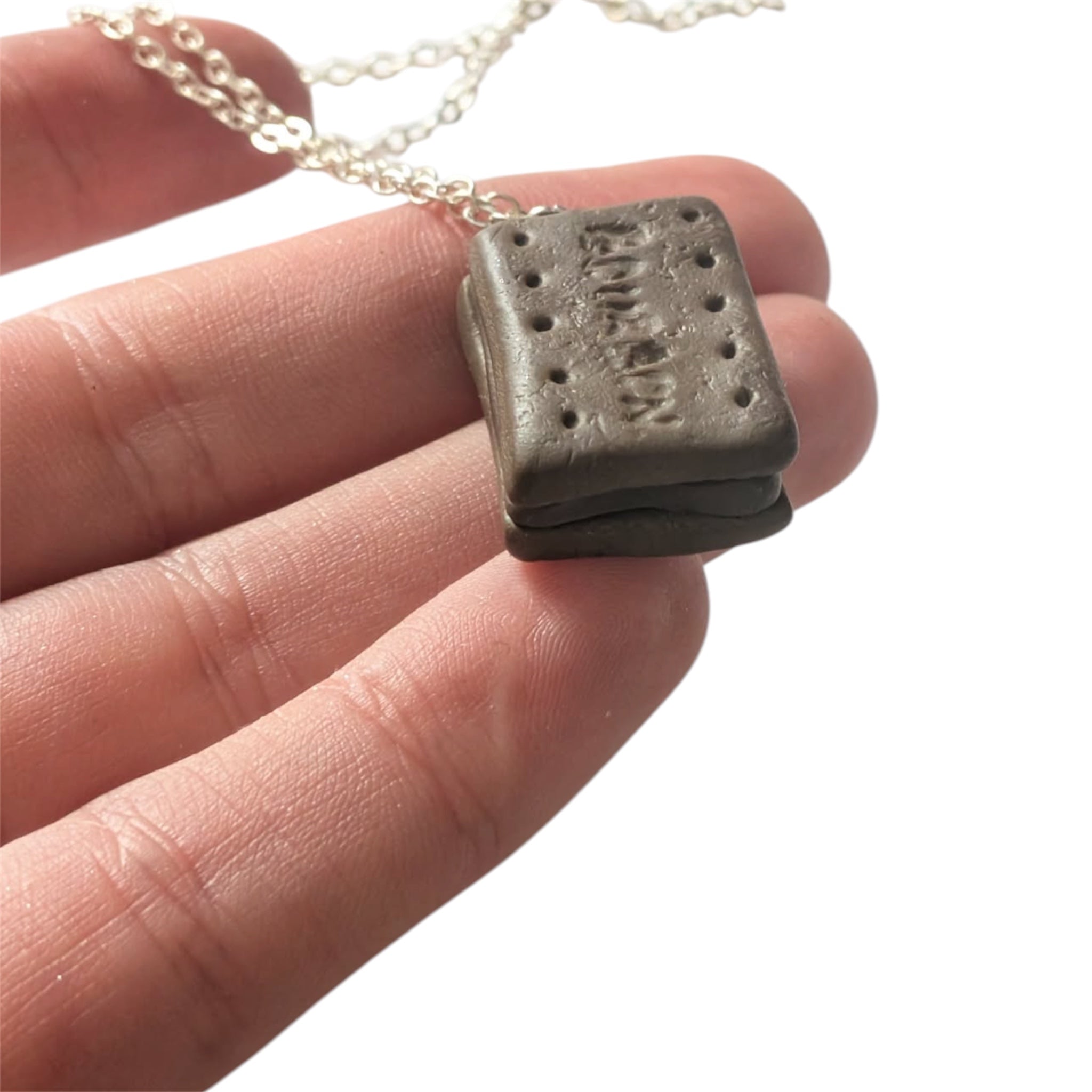 Hand holding mini bourbon biscuit shaped pendant necklace handmade jewellery UK