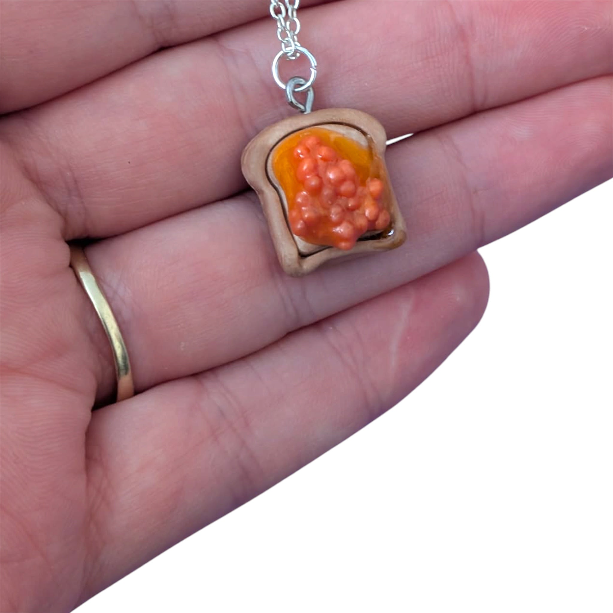Hand holding beans on toast pendant with orange beans made with resin 