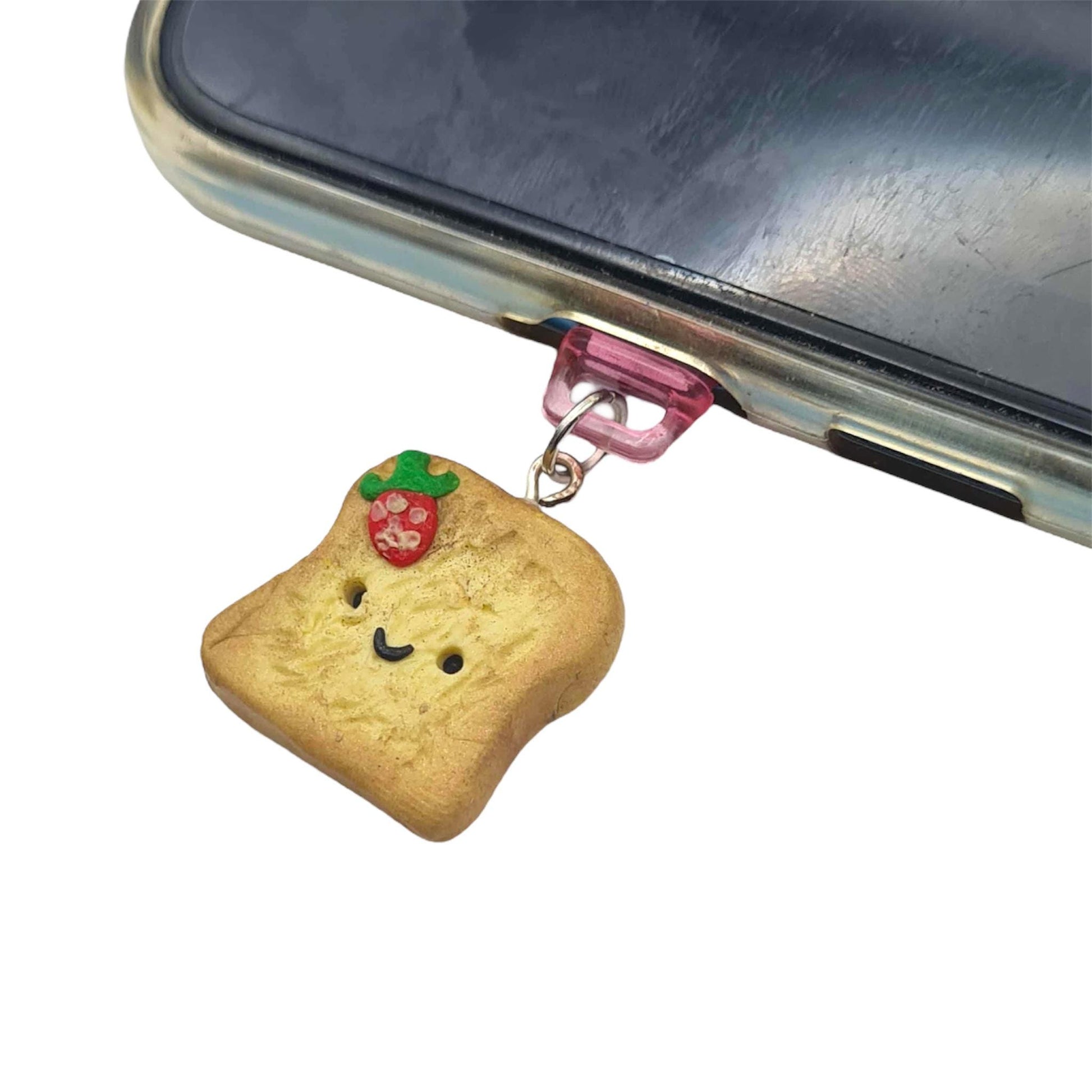 Phone charm shaped like a piece of bread with a face attached to a phone.