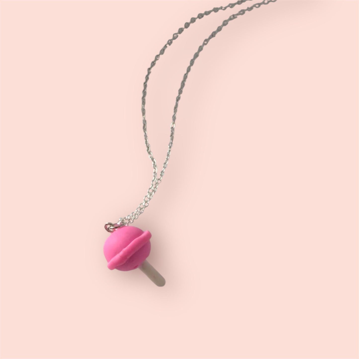 Necklace with a pink pendant on a light pink background