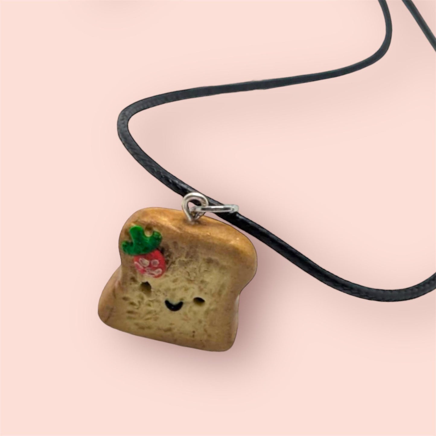 Necklace with a bread-shaped pendant on a pink background