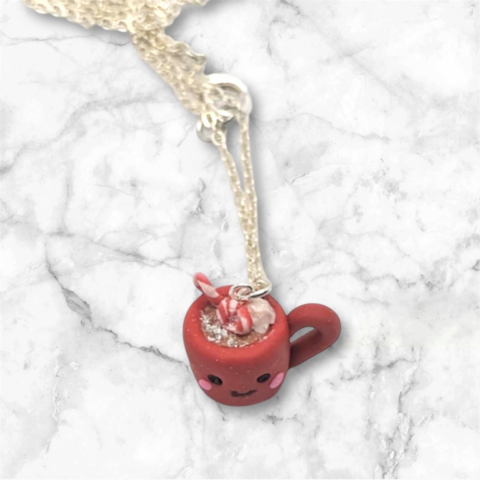 Top of mug with downward camera angle showing whipped cream candy cane and chocolate drink inside a red mug on a marble background 