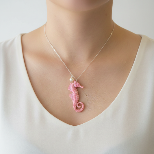 Pink sparkly seahorse necklace with pearl accent worn on model's neck showing how pendant sits