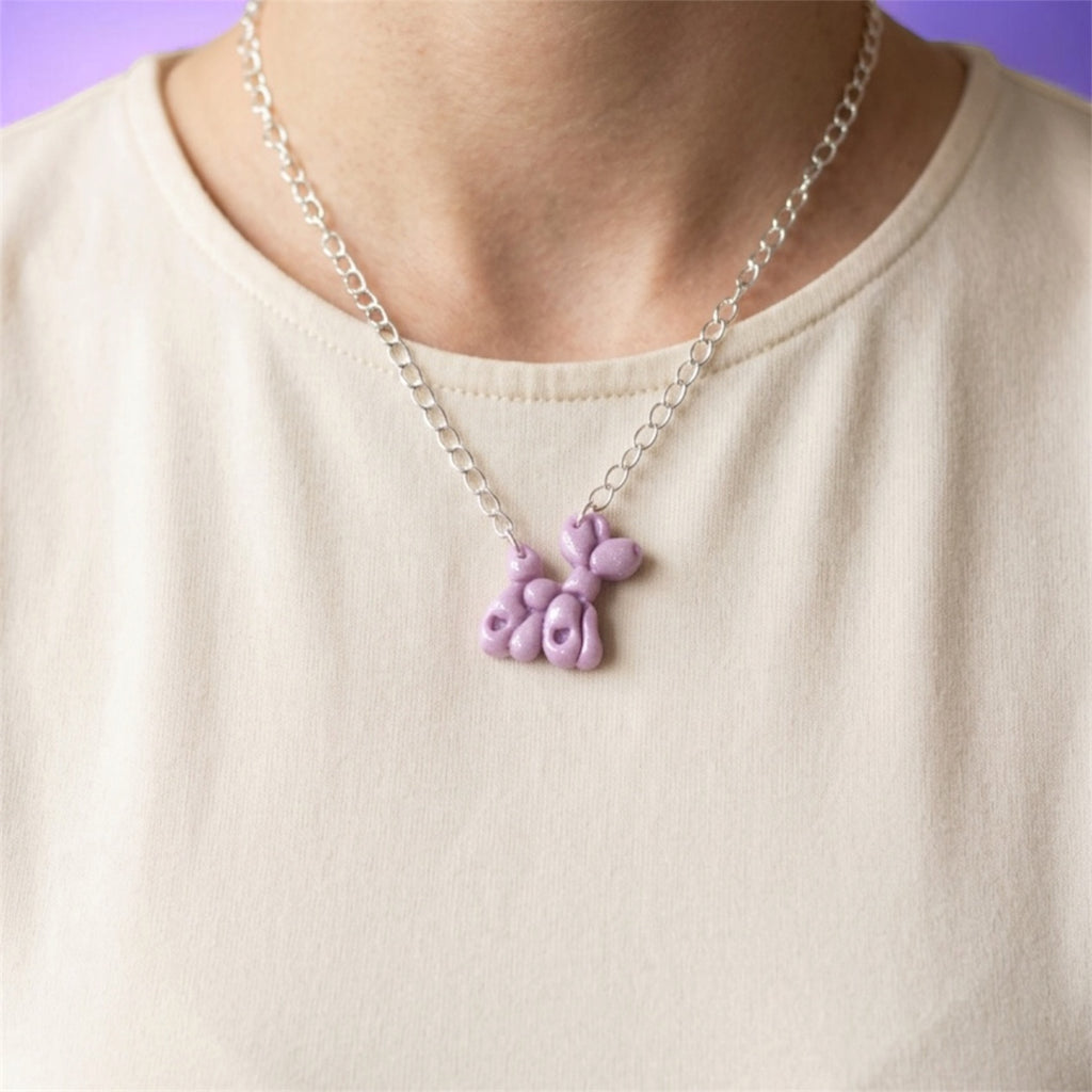 Lilac balloon dog necklace worn with a light-coloured top