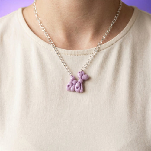 Lilac balloon dog necklace worn with a light-coloured top