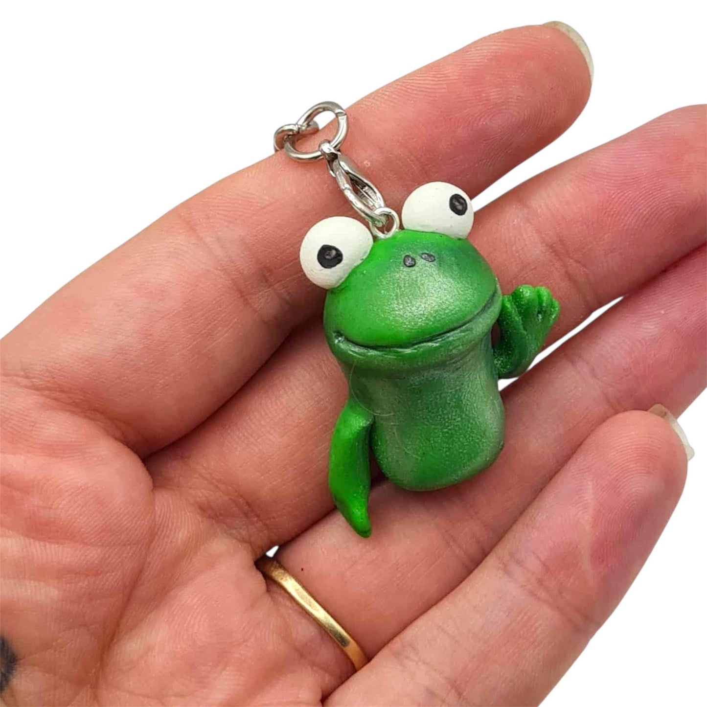 Green frog-shaped keychain held in a hand with a white background