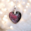 Heart-shaped stone pendant on a chain against a blurred light background