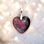 Heart-shaped stone pendant on a chain against a blurred light background