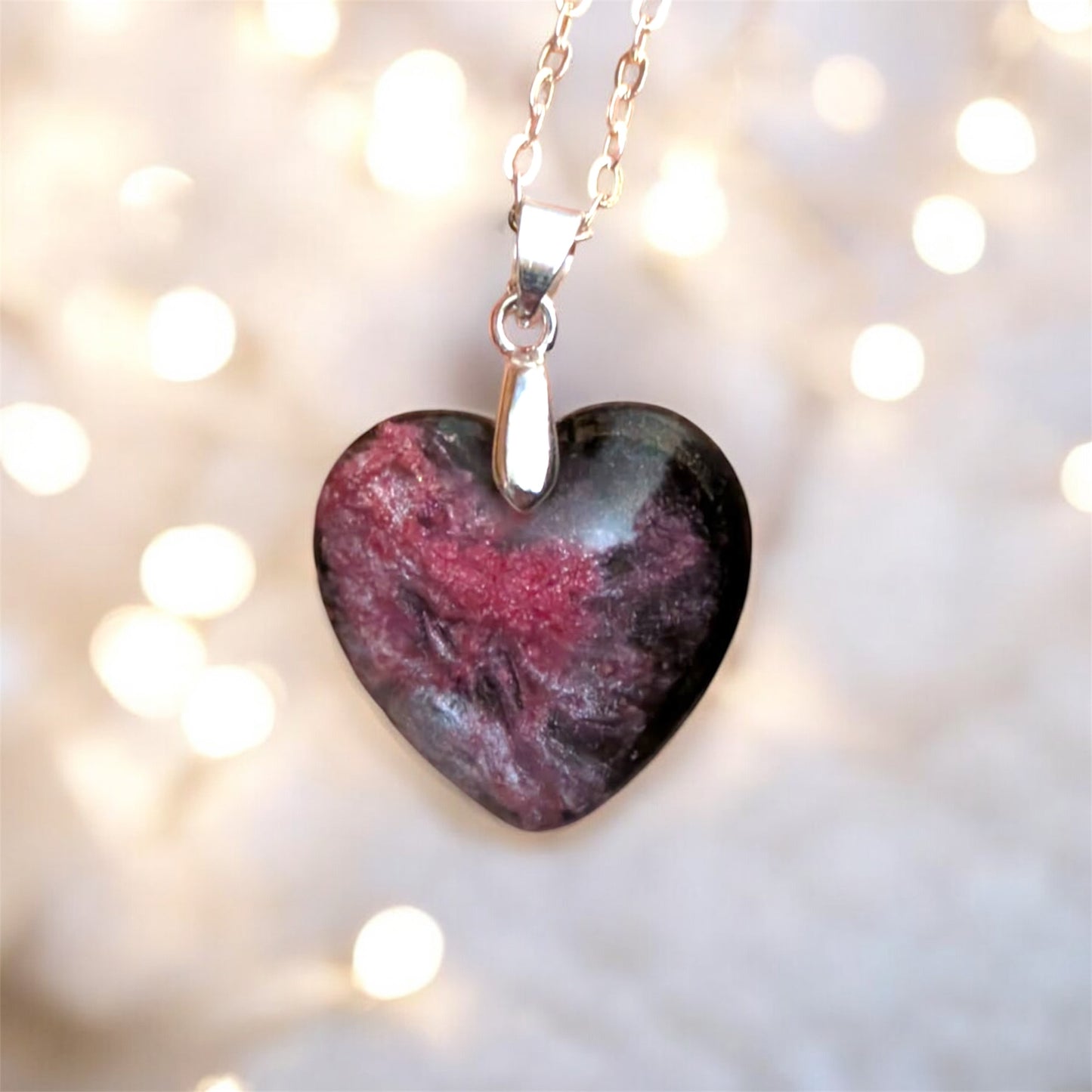 Heart-shaped stone pendant on a chain against a blurred light background