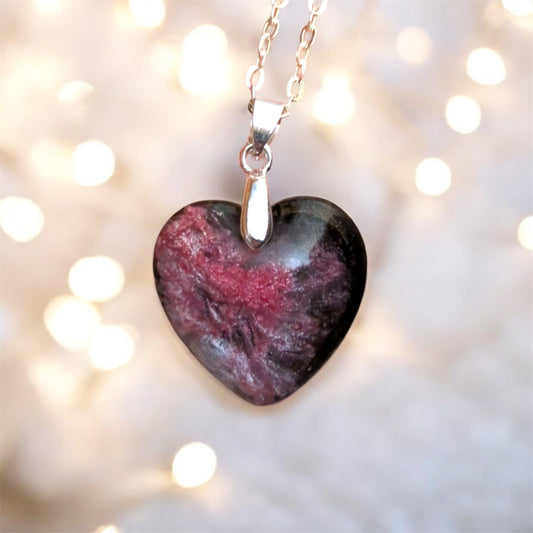 Heart-shaped stone pendant on a chain against a blurred light background