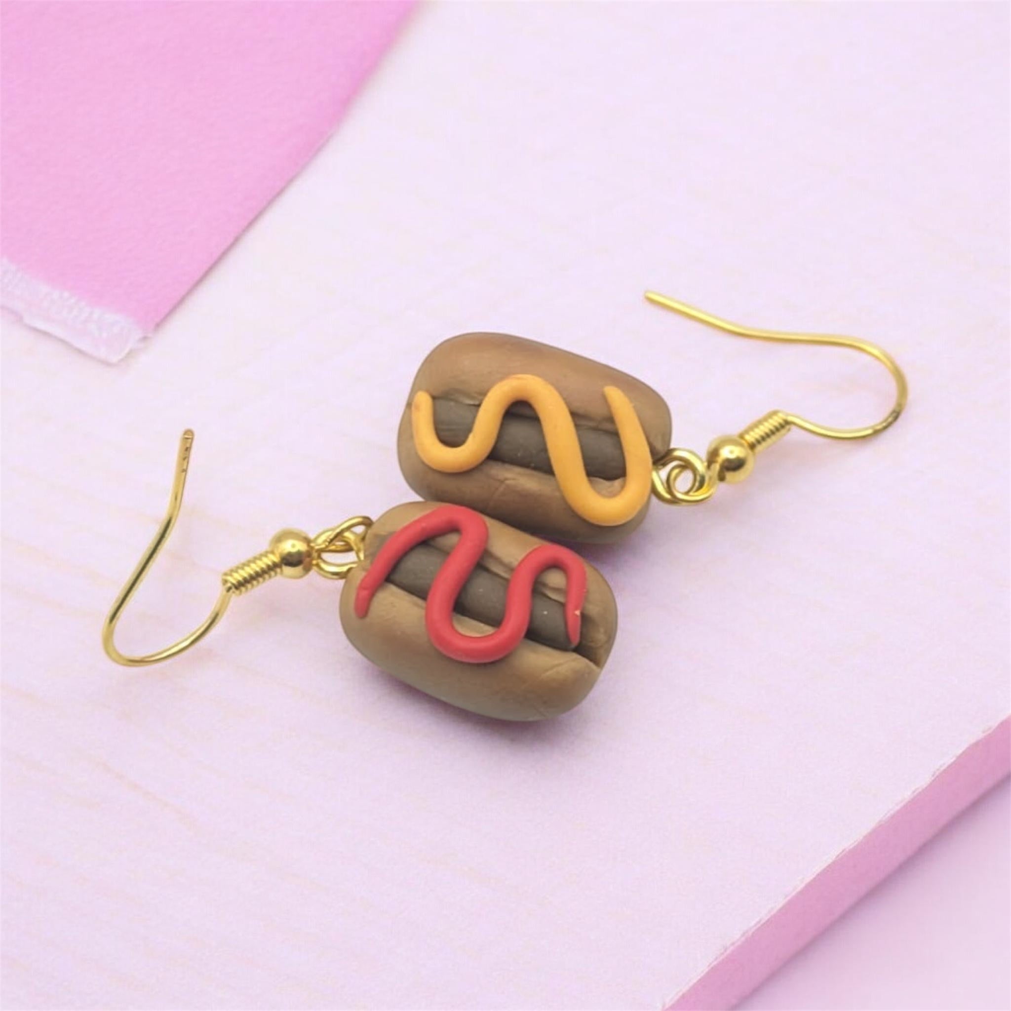 Kawaii hot dog polymer clay dangle earrings on pink pastel background 