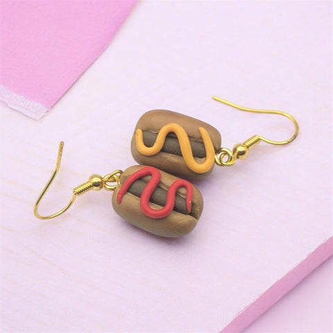 Kawaii hot dog polymer clay dangle earrings on pink pastel background 