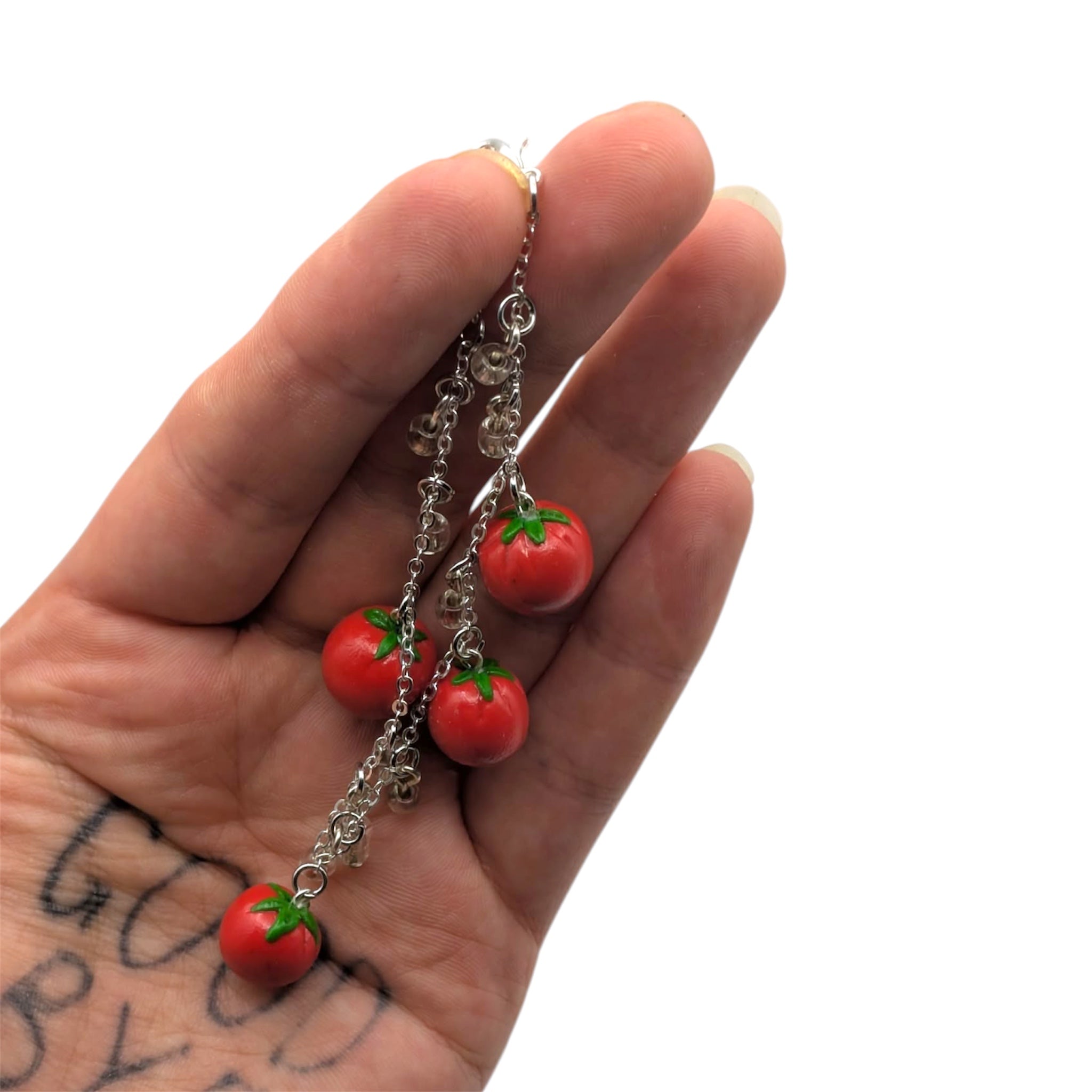 Hand holding tomato-shaped charm bracelet on   a white background
