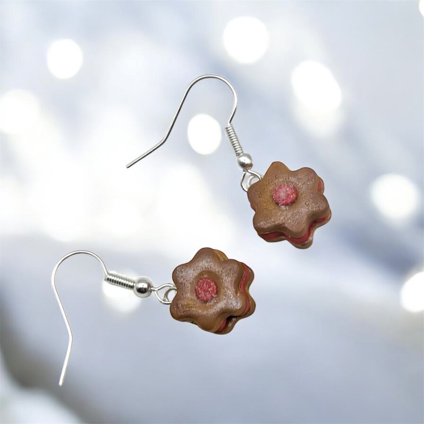 Flower-shaped earrings with pink centers on a blurred light background
