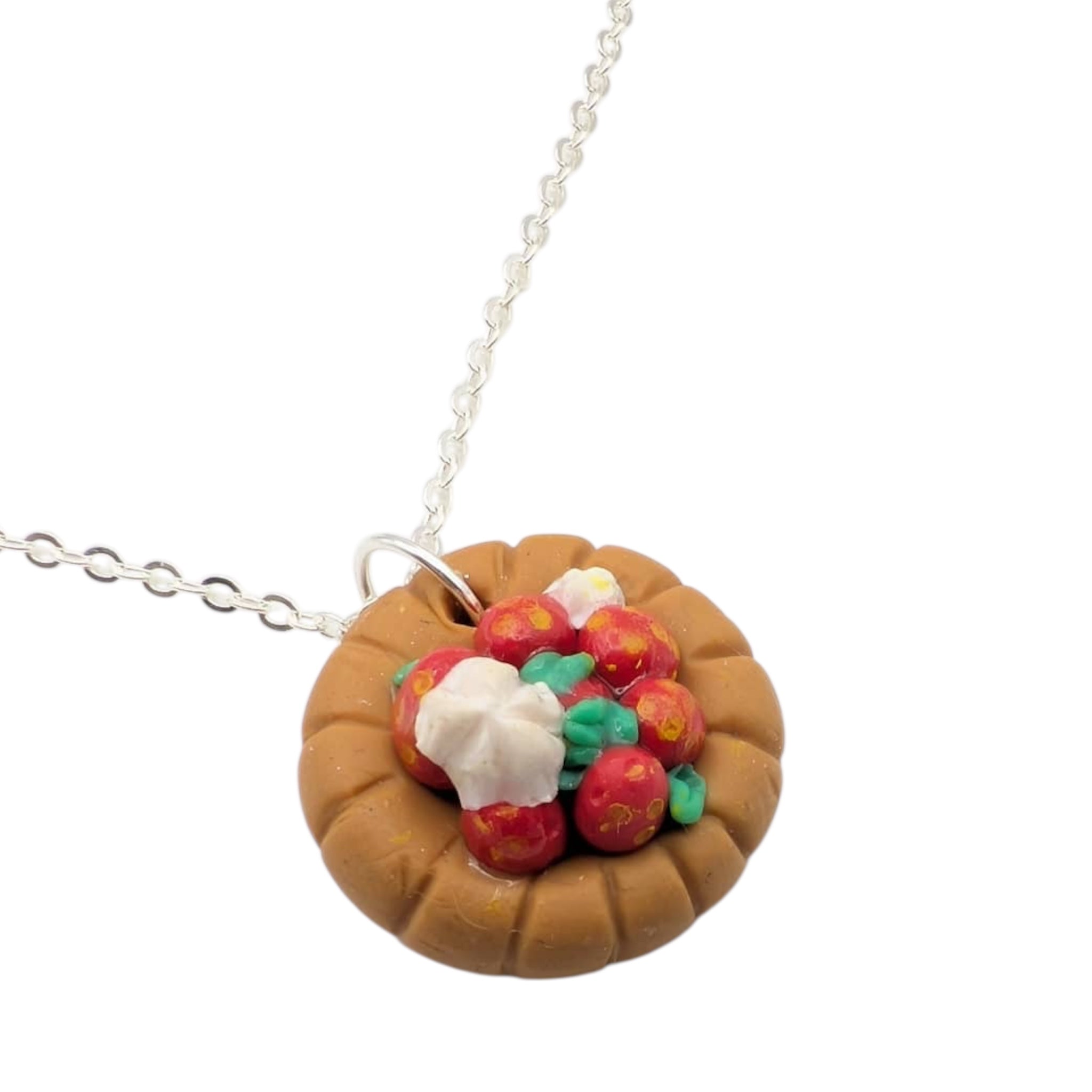 Close up of strawberry tart pendant with silver chain on white background 