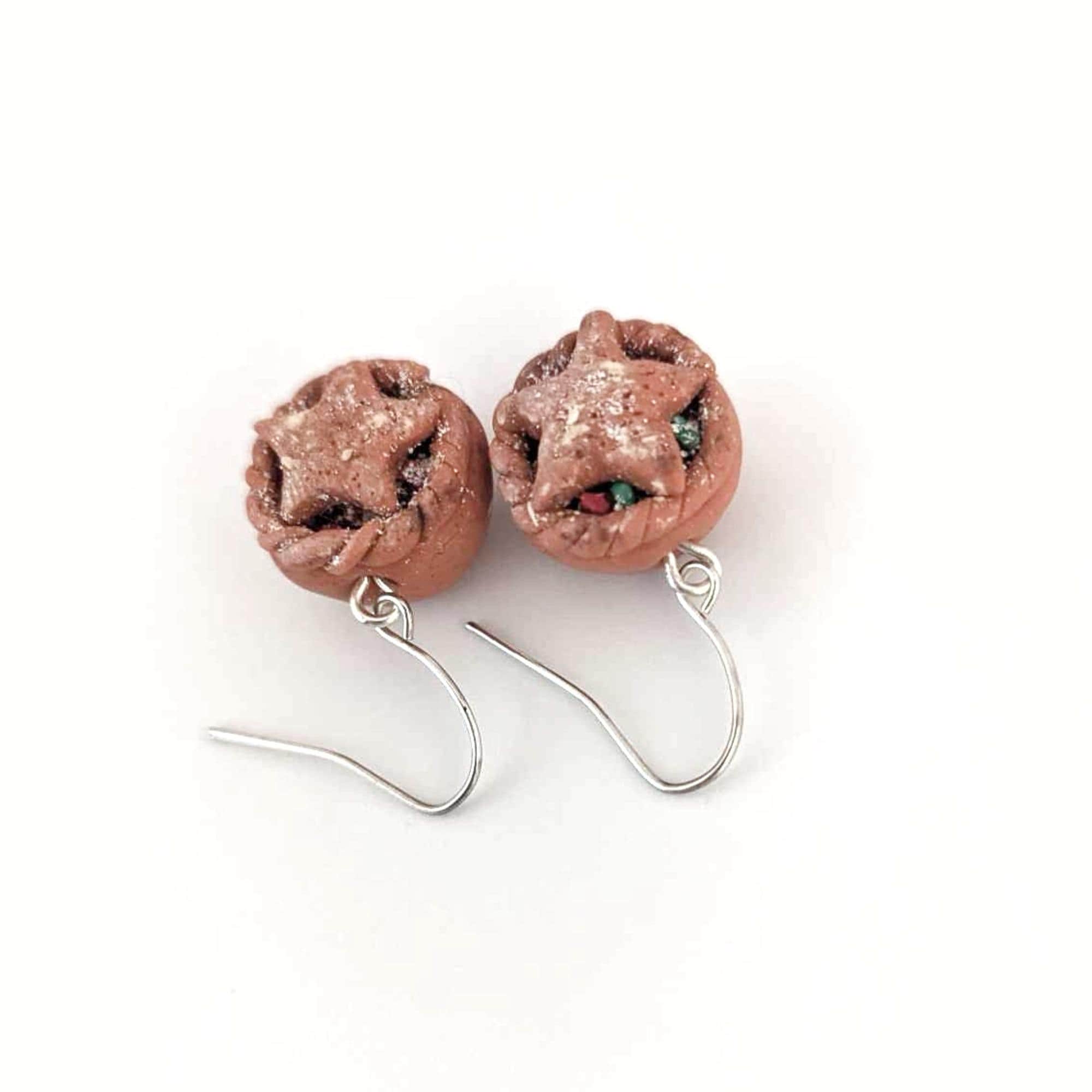 Pair of earrings with star-shaped top on a beige base on a white background