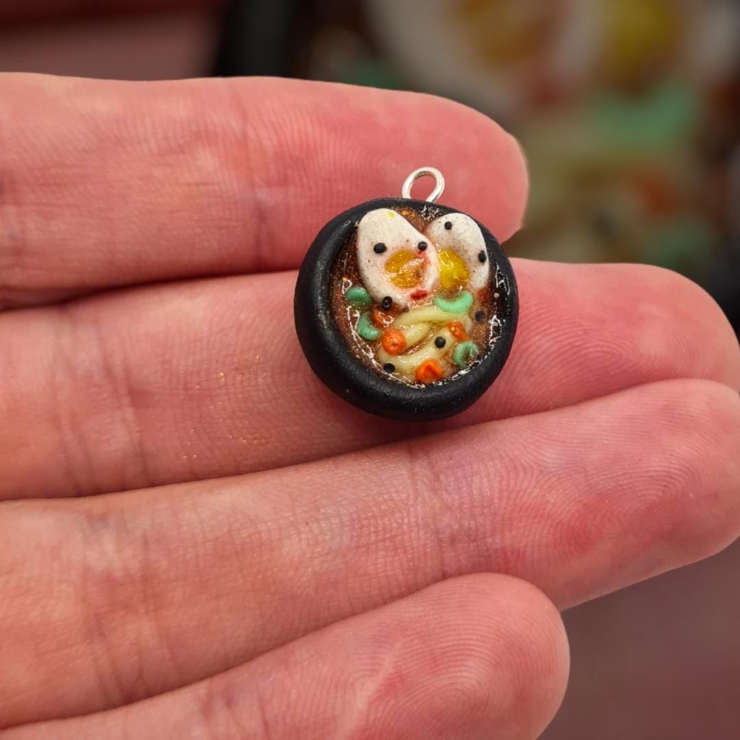 Small round pendant with a design held between fingers