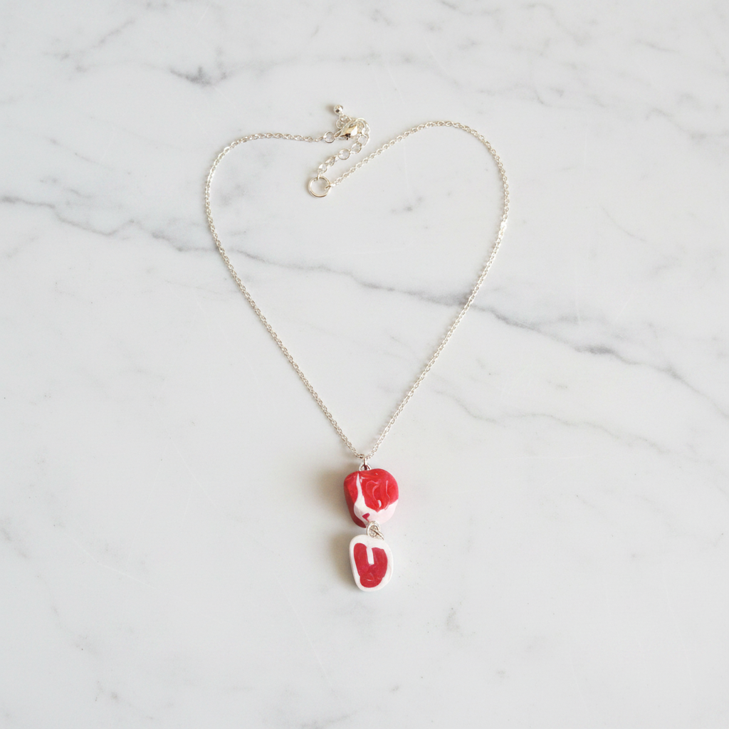 Red and white raw steak necklace on a white background