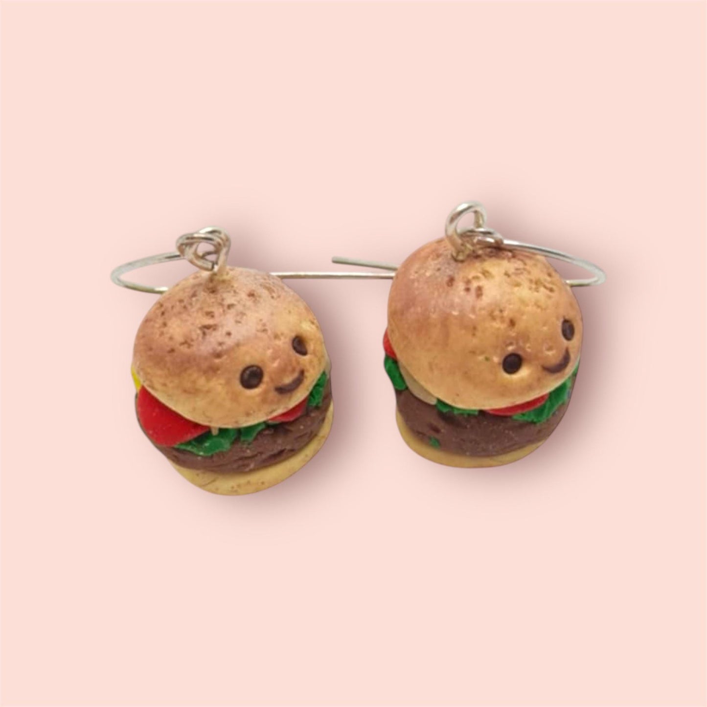 Burger-shaped earrings on a pink background
