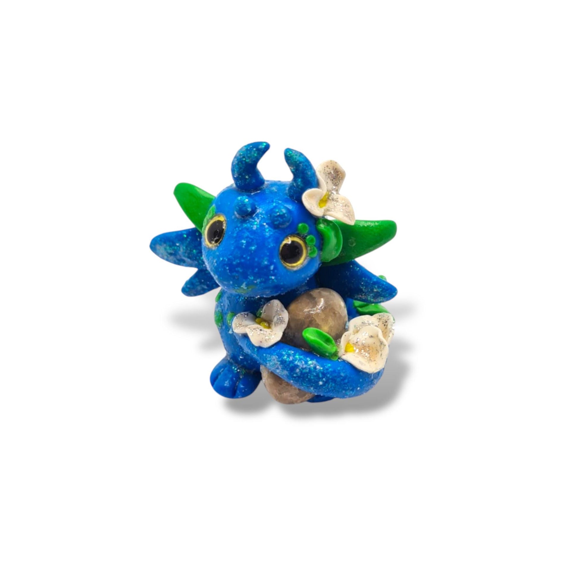 Blue dragon figurine with green accents and flowers on a white background