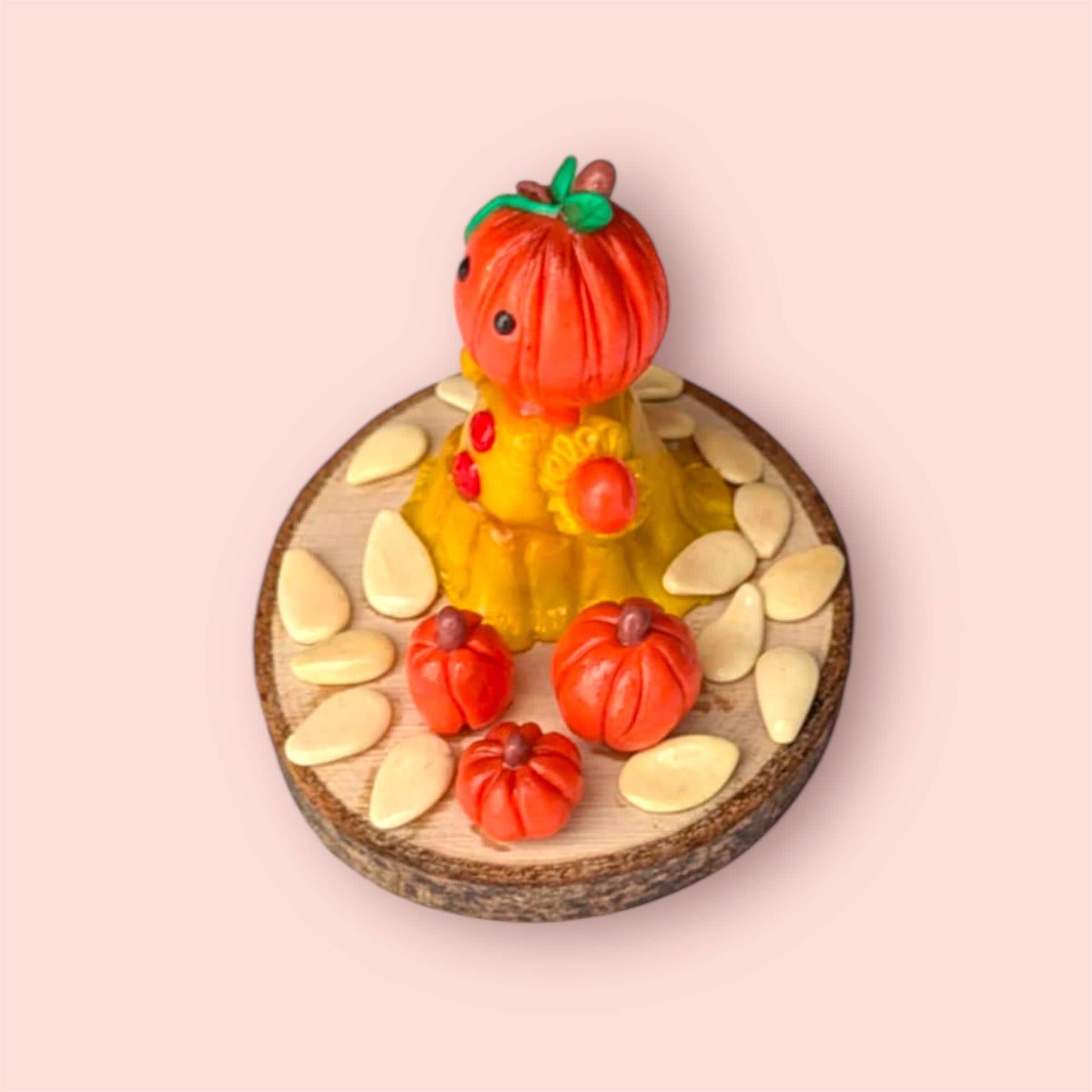 Side view of polymer clay pumpkin sculpture on a pink background