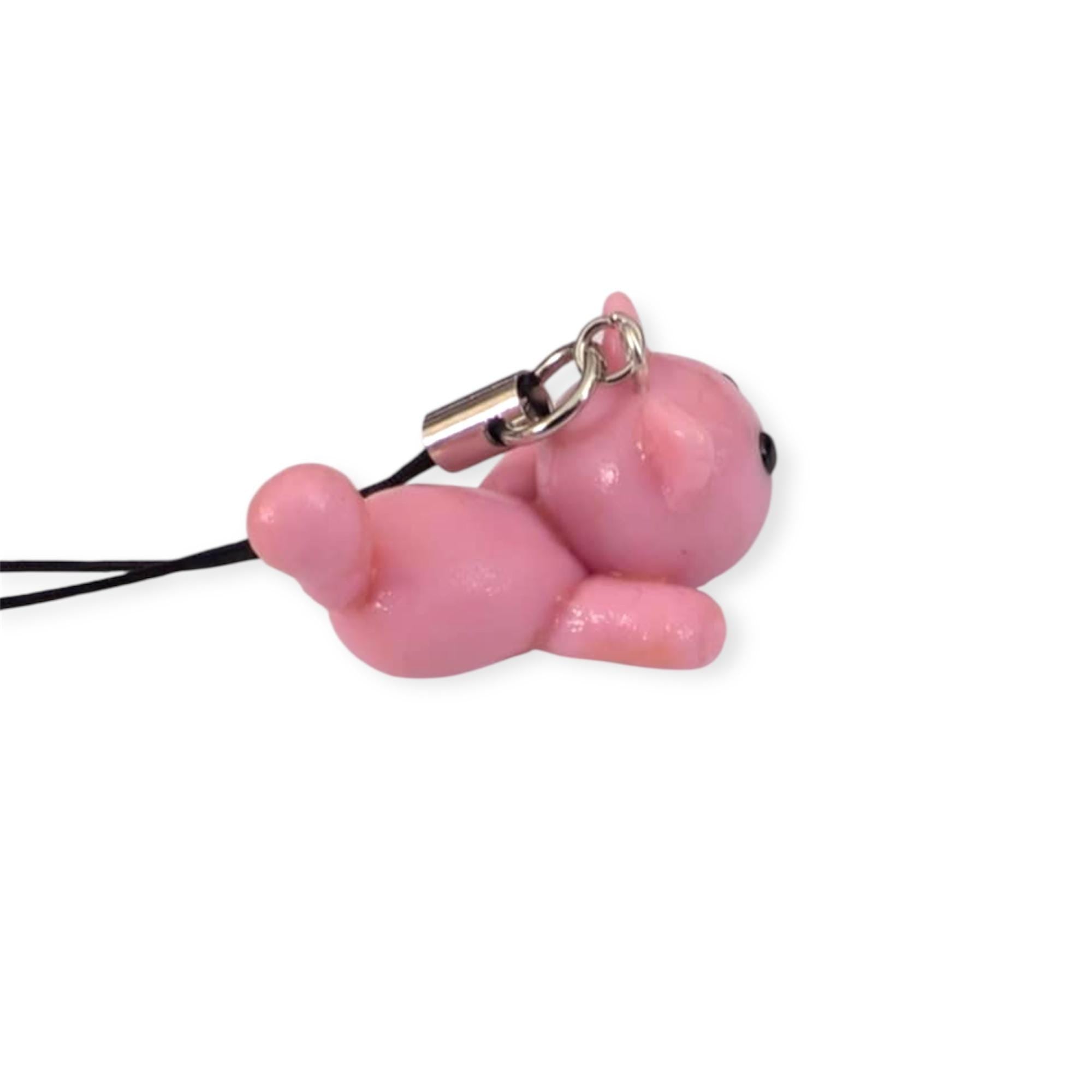 Pink cat-shaped phone charm on a white background