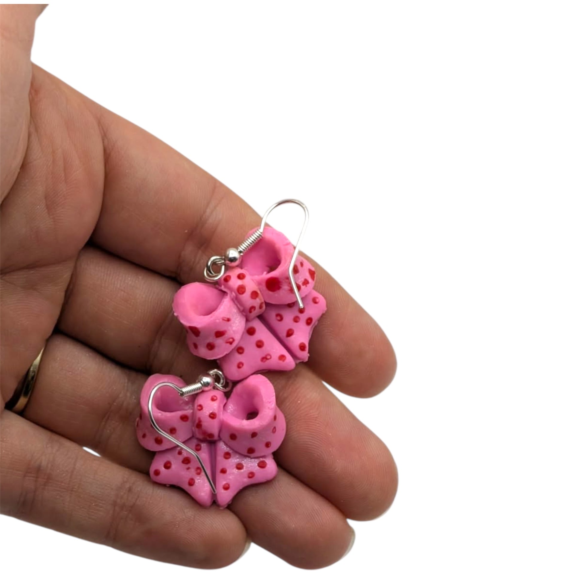 Pink bow polymer clay earrings with silver plated hooks on white background
