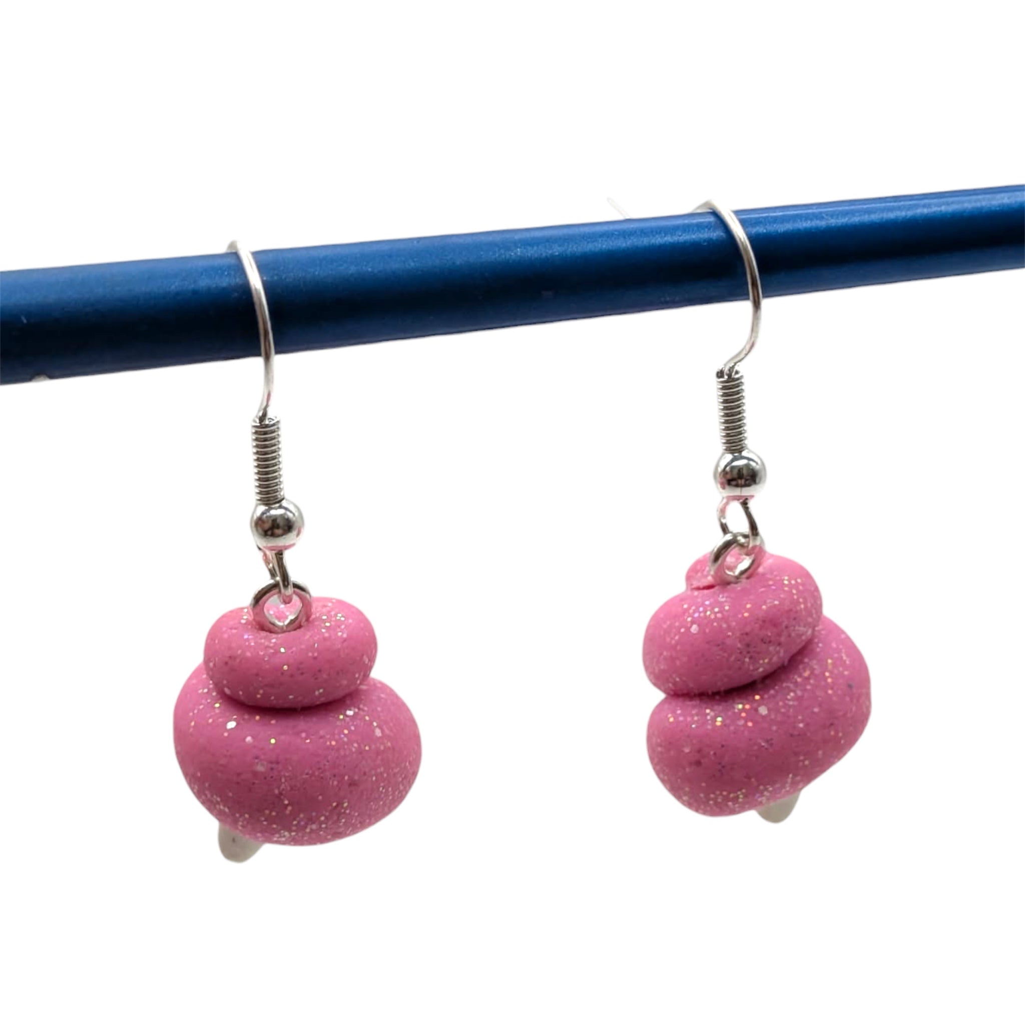 Handmade candy floss earrings hanging from a blue rod, crafted in pink with a sparkly finish from The Circus Collection.