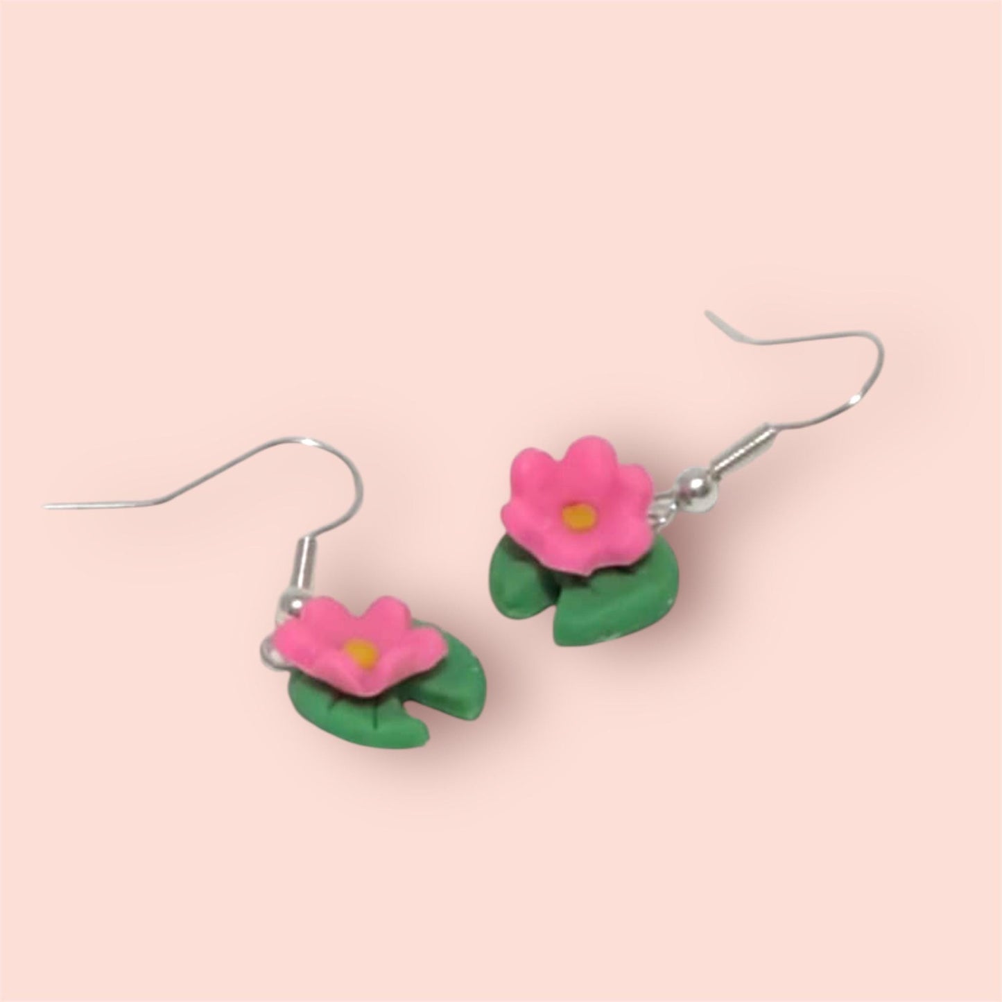 Flower-shaped earrings on a pink background
