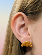Croissant stud earring worn in earlobe  on pastel background 