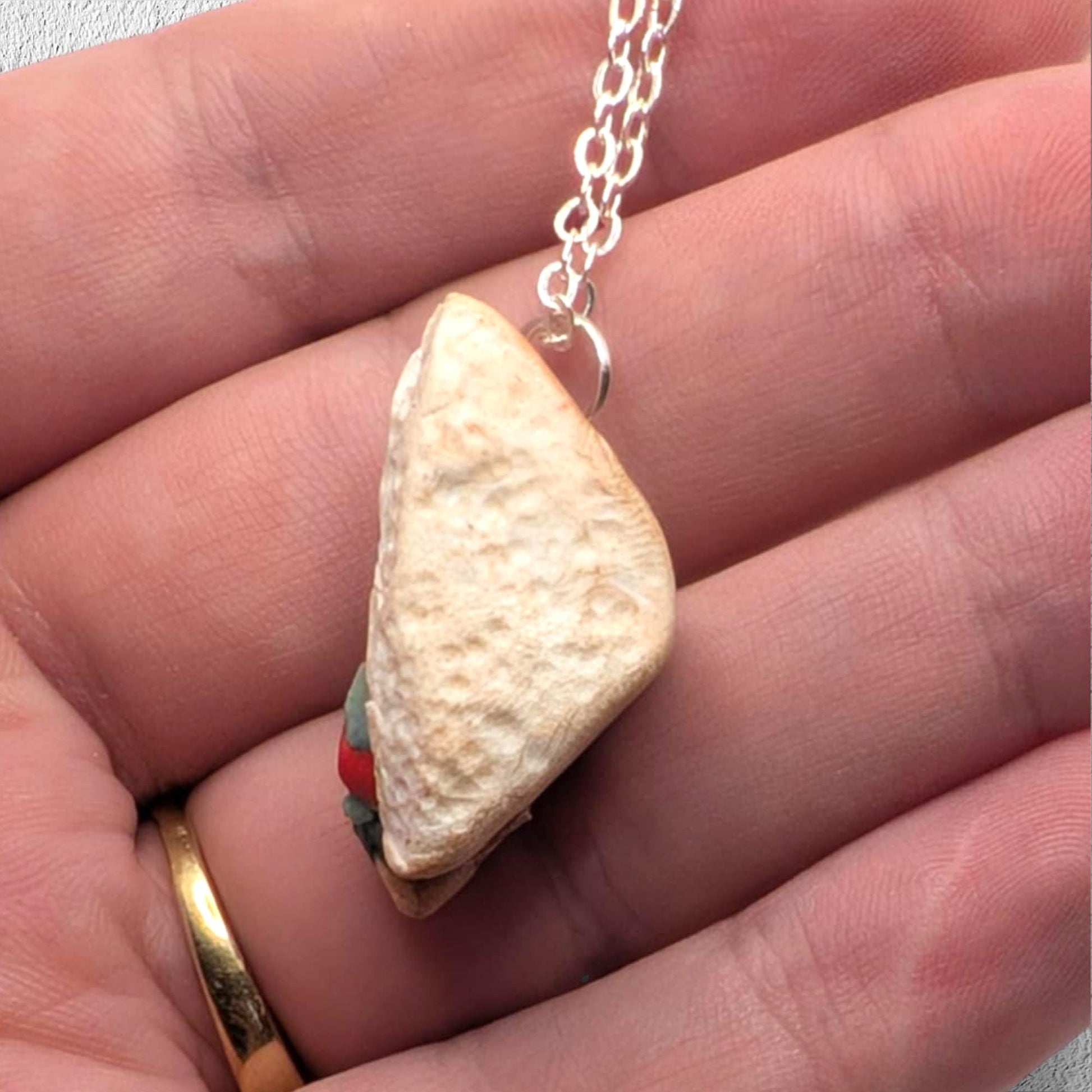 Necklace with a unique pendant held between fingers