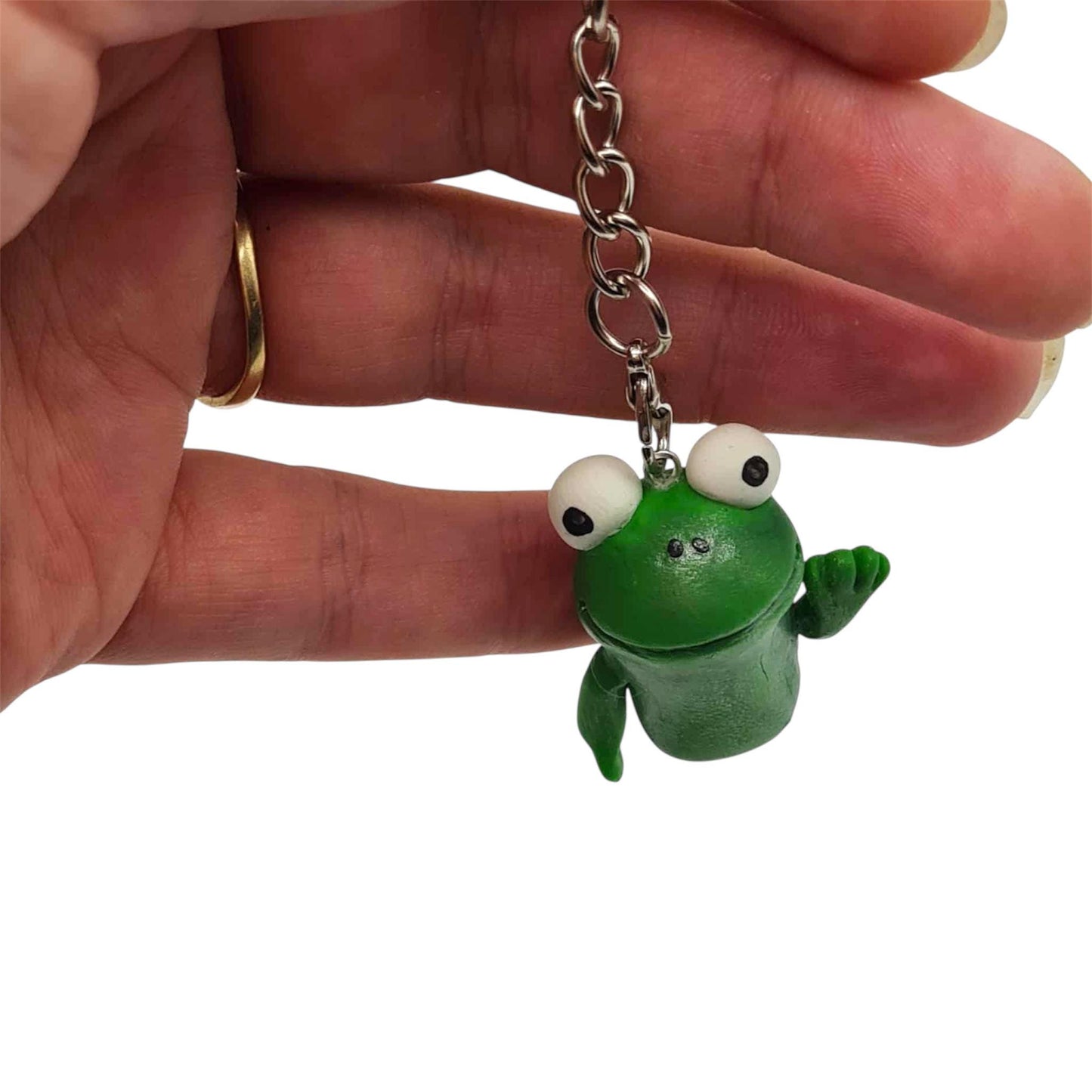 Green frog keychain held by a hand on a white background