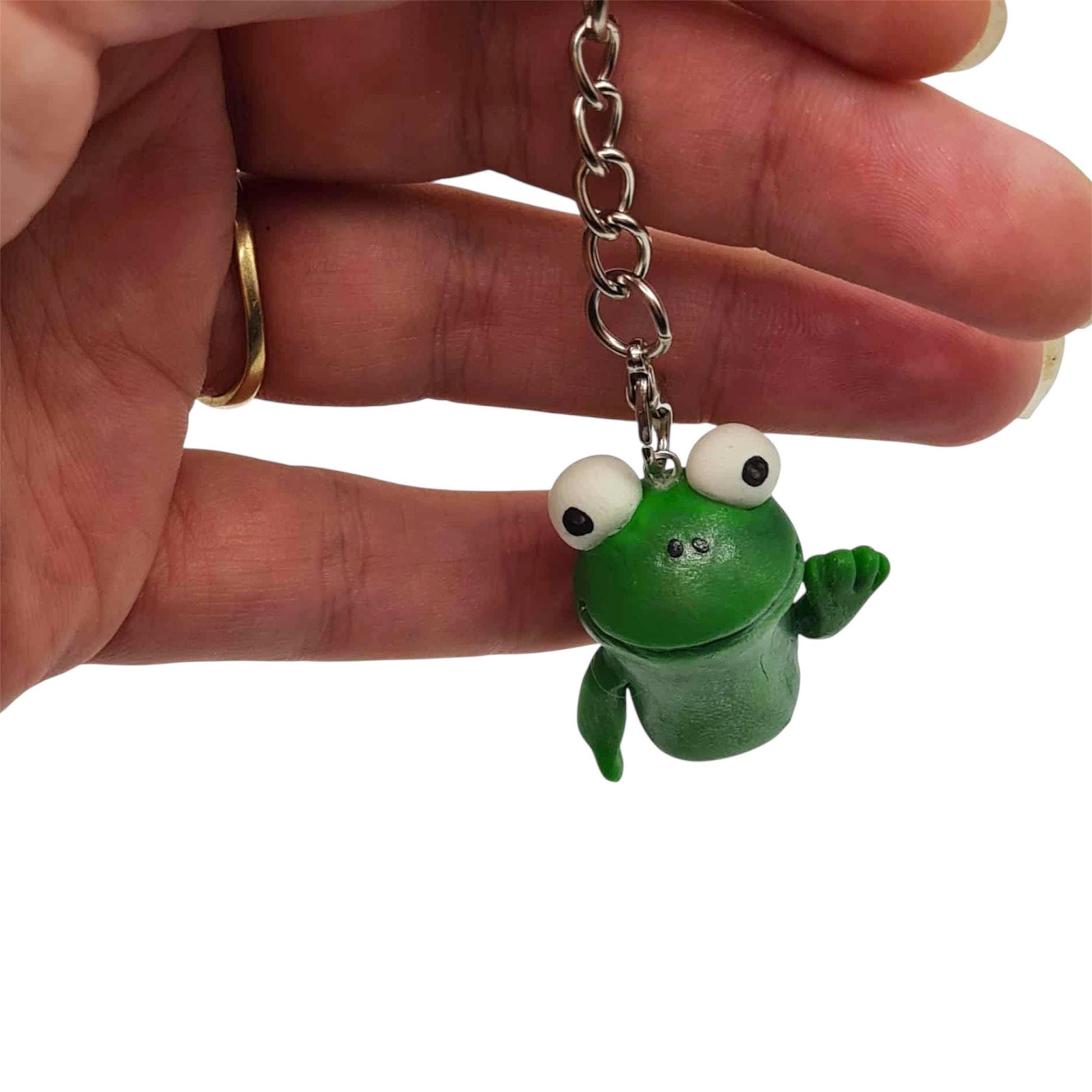 Green frog keychain held by a hand on a white background