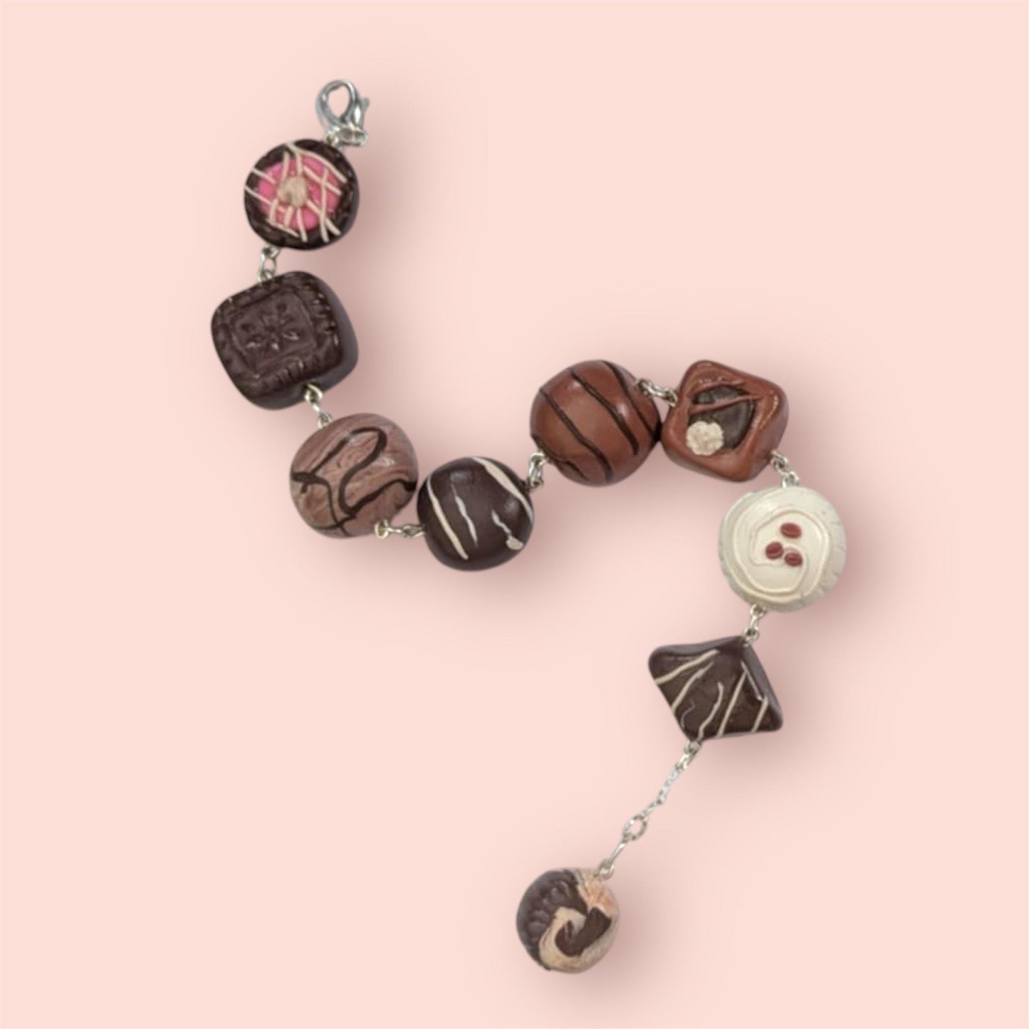 Bracelet with chocolate-themed beads on a pink background