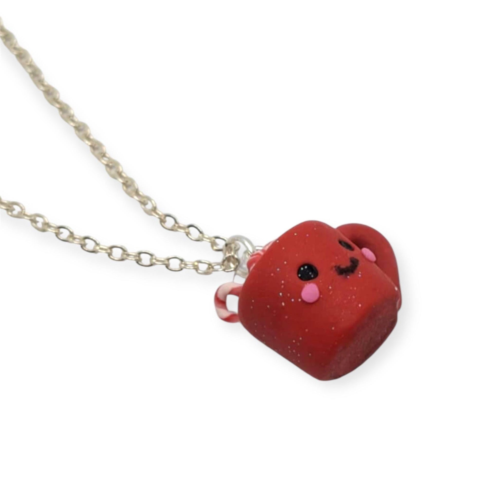 Close up of festive red mug with kawaii face and silver chain on white background 