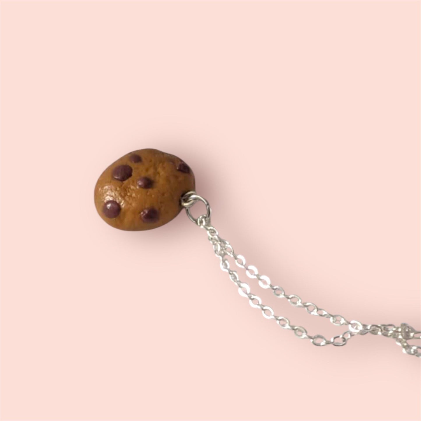 Cookie-shaped pendant with a chain on a pink background