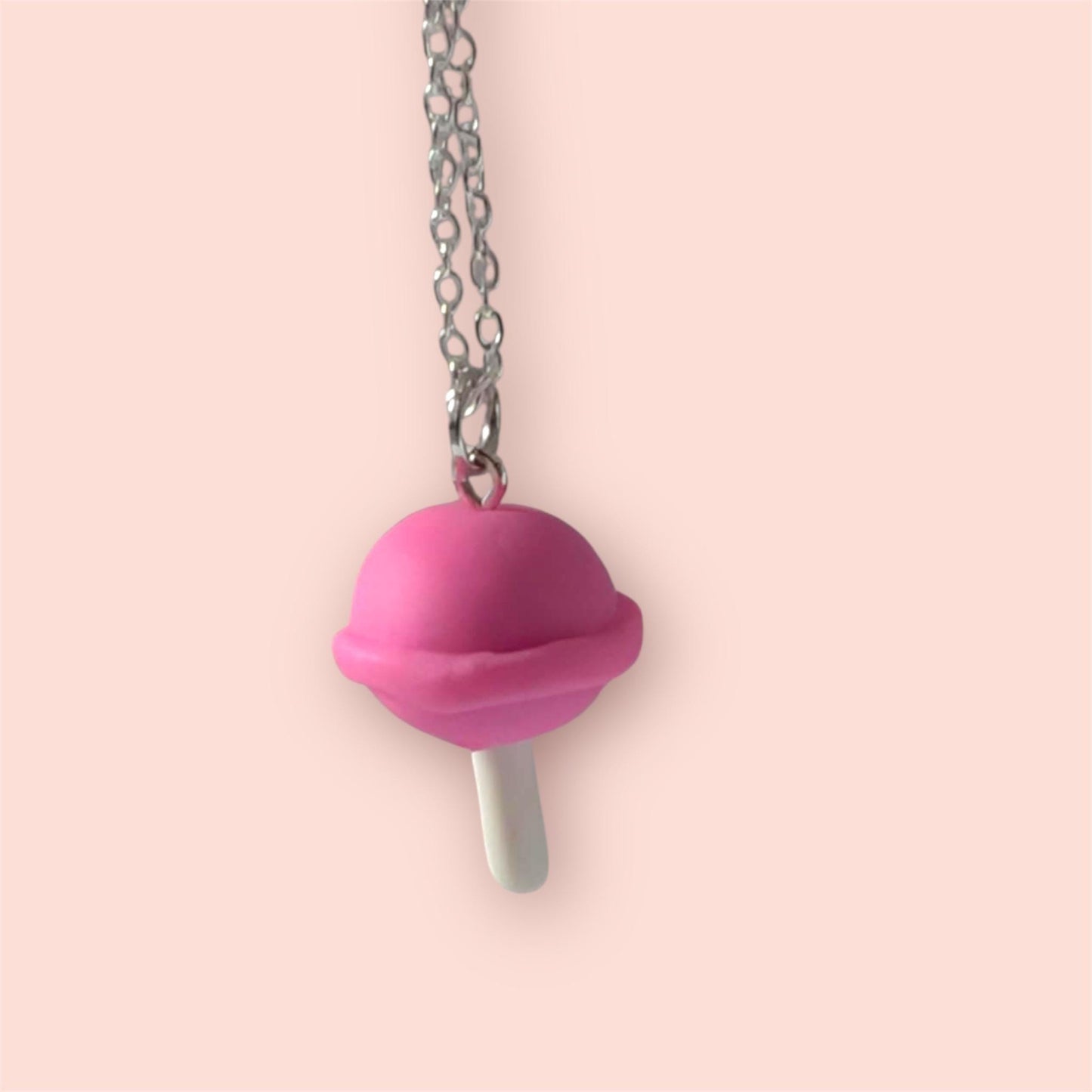 Necklace with a pink sucker pendant on a light pink background