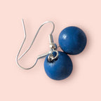 Blue spherical earrings on a pink background