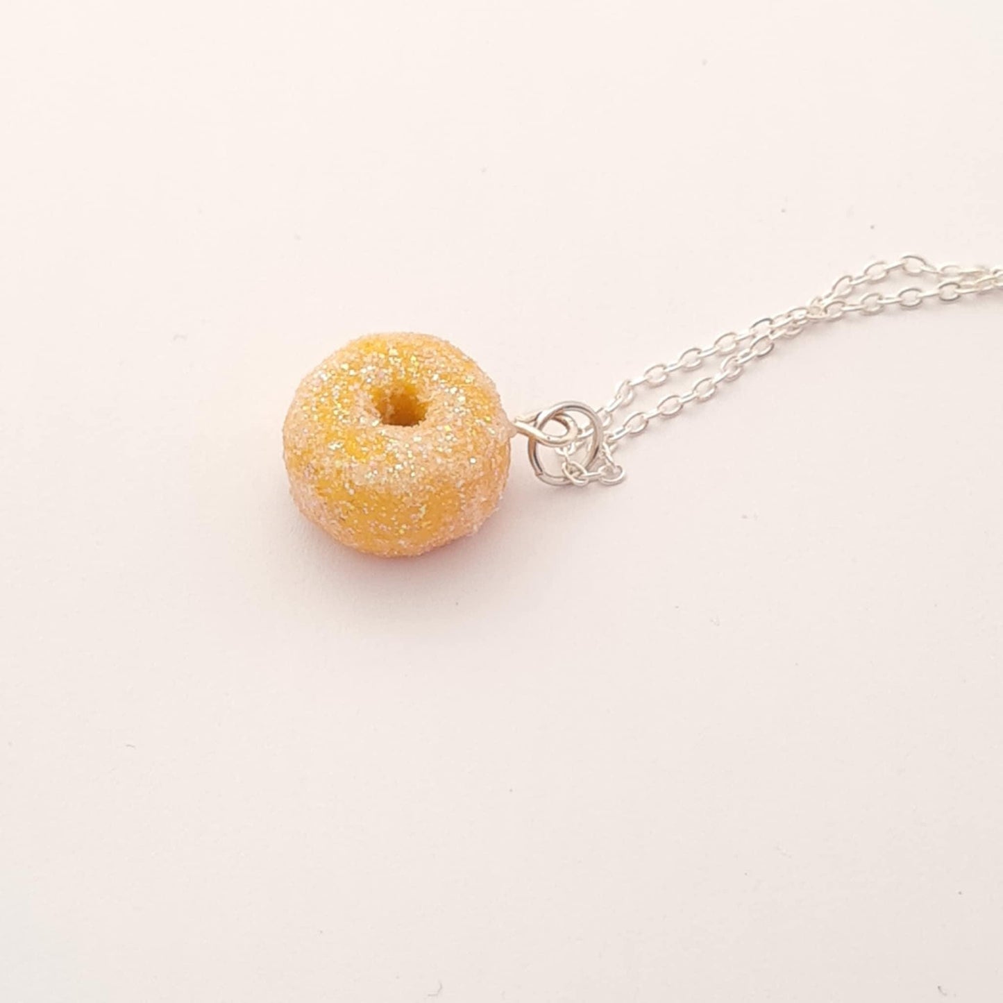 Donut-shaped pendant on a silver chain against a white background